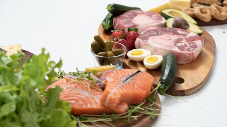 Lachs, Fleisch, Eier, Käse und Gemüse auf Holzbrettern, von oben fotografiert